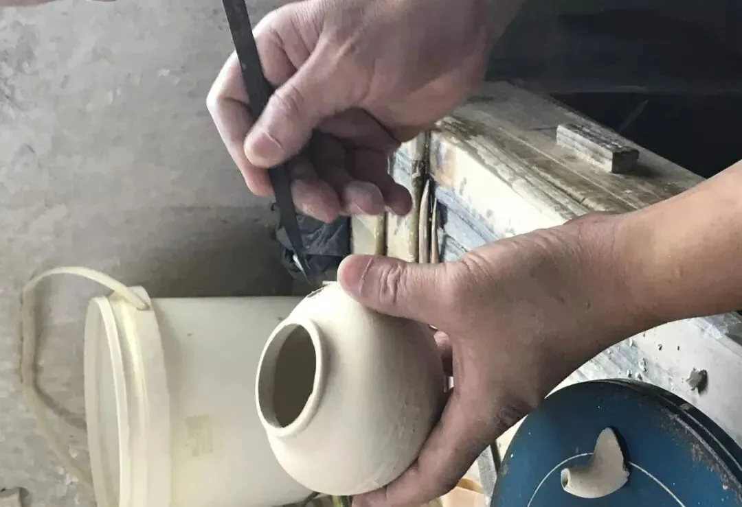 Jingdezhen potter trimming a porcelain vessel by hand